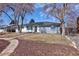 A single story home with a combination of painted brick and lap siding and mature trees in the front yard at 555 W Peakview Ave, Littleton, CO 80120