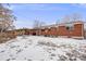 A view of the home's backyard with a red brick exterior and snow covered ground at 8331 Mason Cir, Westminster, CO 80031