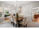 Elegant dining room with a wood table, upholstered chairs, and open access to the living room and staircase at 306 Monares Ln, Erie, CO 80516