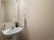 The powder room features a stylish pedestal sink, a decorative mirror, and neutral decor at 306 Monares Ln, Erie, CO 80516