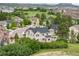 Aerial view of a tan two-story house in a golf community with tree-lined streets and stunning mountain views at 1788 Holmby Ct, Castle Rock, CO 80104