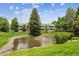 Condominiums overlooking a tranquil pond with a fountain, lush landscaping, and mature trees at 8335 Fairmount Dr # 9-201, Denver, CO 80247