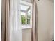 Sunny window with neutral colored curtain and view of trees outside at 8335 Fairmount Dr # 9-201, Denver, CO 80247