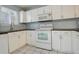 White kitchen with appliances and dark countertops at 1885 S Quebec Way # L102, Denver, CO 80231