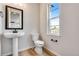 Bathroom with pedestal sink, toilet, wood flooring, and a window at 3314 N Haleyville Ct, Aurora, CO 80019