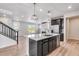 Open kitchen with dark cabinets, quartz island, stainless appliances, and access to living area with fireplace at 3314 N Haleyville Ct, Aurora, CO 80019