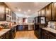 Open-concept kitchen features dark cabinets, stone countertops, and stainless steel appliances at 25120 E Maple Pl, Aurora, CO 80018