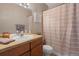 Well-lit bathroom with tile countertop, decorative mirror, and shower with striped curtain at 22610 E Ontario Dr # 204, Aurora, CO 80016