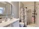 Bright bathroom with white vanity and sink, a large mirror, toilet and a tiled shower at 1560 Olympia Cir # 108, Castle Rock, CO 80104