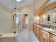 Bright bathroom featuring a glass shower with seat, double vanity, and a peek into the adjacent laundry room at 2590 W Long Cir, Littleton, CO 80120