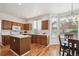 Sunlit kitchen featuring wood cabinets, an island, stainless appliances, and an adjacent dining area at 4290 Cottonwood Lakes Blvd, Thornton, CO 80241