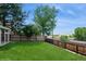 Well-manicured backyard with green lawn, wooden fence, and mature trees at 7325 S Houstoun Waring Cir, Littleton, CO 80120