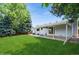 Expansive backyard with a covered patio, lush green lawn, and mature trees for shade and privacy at 7325 S Houstoun Waring Cir, Littleton, CO 80120