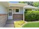 Cozy front porch with brick accents, a white door, and manicured landscaping at 7325 S Houstoun Waring Cir, Littleton, CO 80120