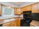 Well-lit kitchen features classic wooden cabinets, black appliances, and laminate countertops at 7325 S Houstoun Waring Cir, Littleton, CO 80120