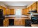 Functional kitchen with wooden cabinets, black appliances, and a window above the sink at 7325 S Houstoun Waring Cir, Littleton, CO 80120
