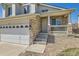 Close-up of the front entrance with stone facade, a covered porch, and a three-car garage at 12771 Clermont St, Thornton, CO 80241
