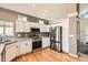 Well-lit kitchen with stainless steel appliances, white cabinets, tile countertops and hardwood flooring at 12771 Clermont St, Thornton, CO 80241