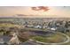 Wide aerial view of a neighborhood including a pond, walking path, and mountain views at sunset at 13753 Jasmine St, Thornton, CO 80602