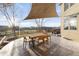 Outdoor patio area with a dining table and chairs, a shade sail, and views of the fenced backyard and community at 13753 Jasmine St, Thornton, CO 80602