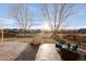 Expansive backyard with mature trees, a play area, and a cozy seating area around a fire pit on a stamped patio at 13753 Jasmine St, Thornton, CO 80602