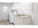 Functional laundry room with modern white cabinets, stainless sink, countertop, and a front-load washing machine at 13753 Jasmine St, Thornton, CO 80602