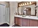 Bathroom featuring double sinks, a bathtub and a shower; complemented by warm lighting and wooden cabinets at 10732 Cook Ct, Northglenn, CO 80233
