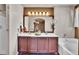 Bathroom featuring double sinks, and a bathtub; complemented by warm lighting and wooden cabinets at 10732 Cook Ct, Northglenn, CO 80233