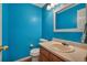 Bright half bathroom features a blue accent wall, wood vanity, and white fixtures at 5149 S Tibet St, Aurora, CO 80015