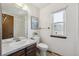 Traditional bathroom with a wood vanity, white sink, and a window providing natural light at 7942 S Vincennes Way, Centennial, CO 80112