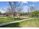 Community playground with a wooden play structure, swings, and seating surrounded by green grass and trees at 7942 S Vincennes Way, Centennial, CO 80112