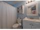 Cozy bathroom featuring blue walls, a shower with a curtain, a commode, and a white vanity with sink at 5431 E 129Th Ave, Thornton, CO 80241