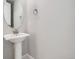 Elegant half bathroom featuring a pedestal sink with modern fixtures and a decorative round mirror at 10371 Harrisburg St, Parker, CO 80134