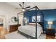 Modern bedroom featuring a four-poster bed, wood floors, and a stylish blue accent wall at 7476 E Arkansas Ave # 35-01, Denver, CO 80231