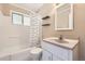 Clean bathroom with a tub and shower combination, featuring a white vanity and practical shelving at 1475 Lucille Ct, Northglenn, CO 80233