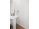 A well-lit bathroom featuring a pedestal sink, wood flooring, and neutral decor at 5880 W 39Th Pl, Wheat Ridge, CO 80212