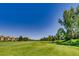 A well-manicured golf course with vibrant green grass, mature trees, and residential buildings in the distance at 2700 W Riverwalk Cir # C, Littleton, CO 80123