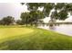 Lush golf course view featuring a flag on the green, a tranquil pond, and mature trees under an overcast sky at 2700 W Riverwalk Cir # C, Littleton, CO 80123