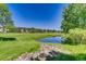Expansive green space featuring a pond and trees, with apartments in the background under a clear blue sky at 2700 W Riverwalk Cir # C, Littleton, CO 80123