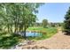Picturesque view of a pond surrounded by lush greenery and trees, with residential buildings in the background at 2700 W Riverwalk Cir # C, Littleton, CO 80123