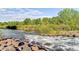 Beautiful river view featuring gentle rapids over rocks, lush greenery, and a serene water landscape at 2700 W Riverwalk Cir # C, Littleton, CO 80123