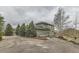 Exterior shot of this property featuring a paved driveway, manicured trees, and an open field in the background at 11020 E 150Th Pl, Brighton, CO 80602