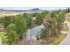 Aerial view of a wooded property with a gray home, surrounded by mature trees and mountain views at 4185 Cheyenne Dr, Larkspur, CO 80118