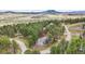 Aerial view of a beautiful home nestled amongst towering trees, and a green landscape at 4185 Cheyenne Dr, Larkspur, CO 80118