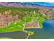 Picturesque aerial view featuring a lush golf course, a serene lake, and a hilly landscape at 4185 Cheyenne Dr, Larkspur, CO 80118
