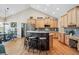 Bright kitchen with hardwood floors, light wood cabinets, island seating, and stainless steel appliances at 4185 Cheyenne Dr, Larkspur, CO 80118
