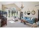 Bright living room featuring large windows, high ceilings, and a stylish blue sofa with decorative mirrors at 4185 Cheyenne Dr, Larkspur, CO 80118