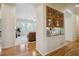 A hallway with wooden floors, white walls, and arched doorways leads to the living room and wet bar at 8068 Dressage Rd, Littleton, CO 80125