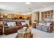 A living room with leather sofas, a coffee table, and an open floor plan that leads to the kitchen at 8068 Dressage Rd, Littleton, CO 80125