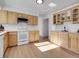 Bright kitchen featuring wood cabinets, white appliances, and light wood flooring at 11427 Brownstone Dr, Parker, CO 80138